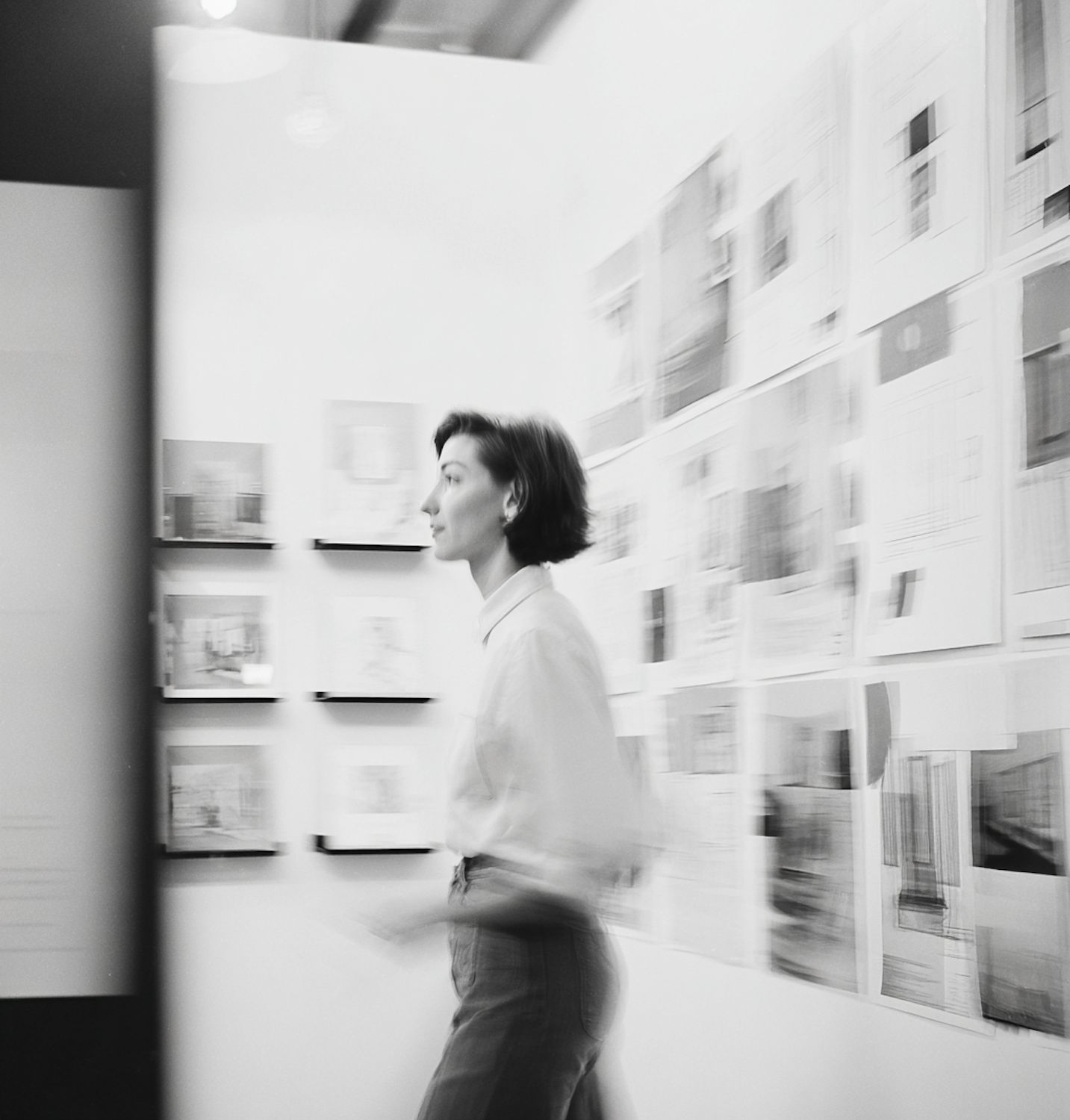 A colleague walking past drawings pinned to the wall of the studio